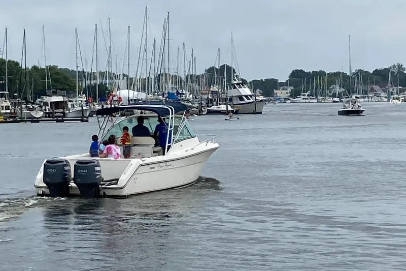 Slide: The Image of 2003 Pursuit 2670 Denali LS boat cruising in a marina with people onboard. - 9