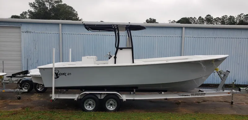 Slide: The Image of 2025 C-Hawk 26 CC boat on trailer, parked outdoors near a blue building. - 1
