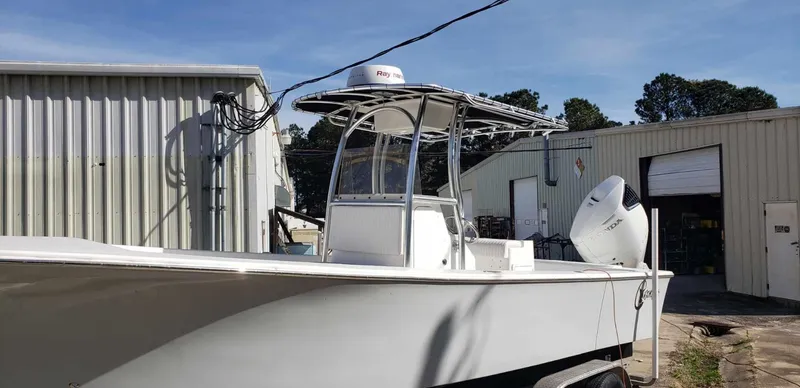 Slide: The Image of 2025 C-Hawk 26 CC boat parked near industrial buildings. - 2