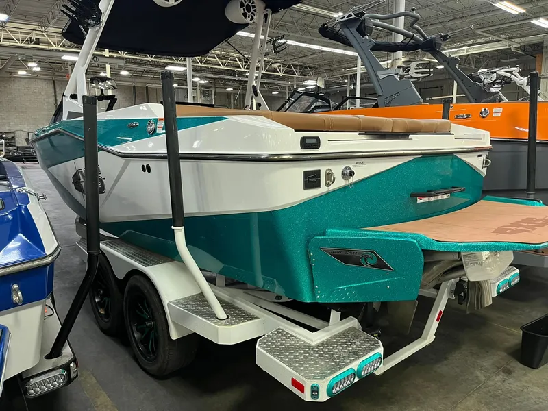 Slide: The Image of 2023 Axis T220 boat in showroom, teal and white design, on a trailer. - 10