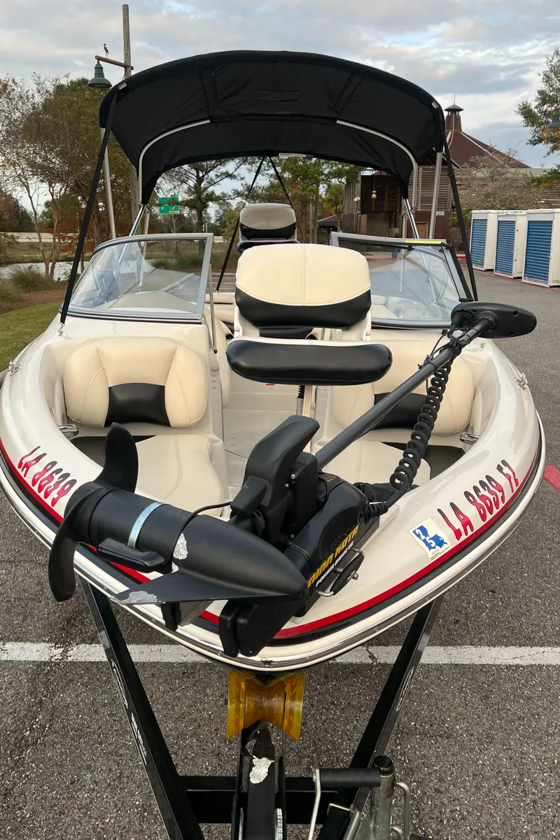 Slide: The Image of 2013 Tahoe Q5i boat with canopy and trolling motor in a parking area. - 11