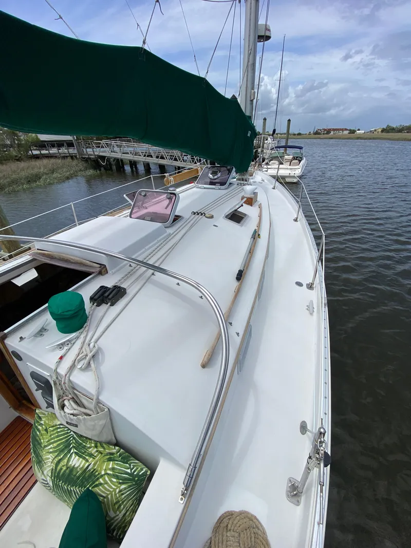 Slide: The Image of 1986 Nonsuch 30 Ultra sailboat on calm water, featuring a spacious deck and green canopy. - 10