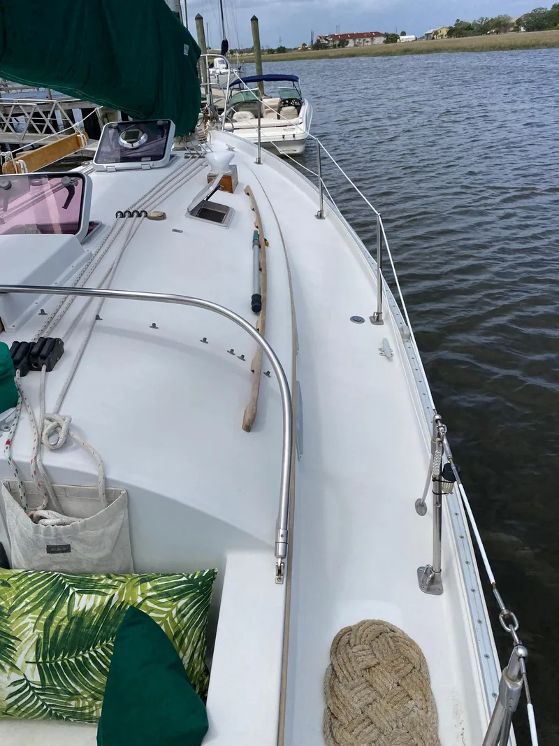 Slide: The Image of 1986 Nonsuch 30 Ultra sailboat deck with green canopy, docked by calm waters. - 11