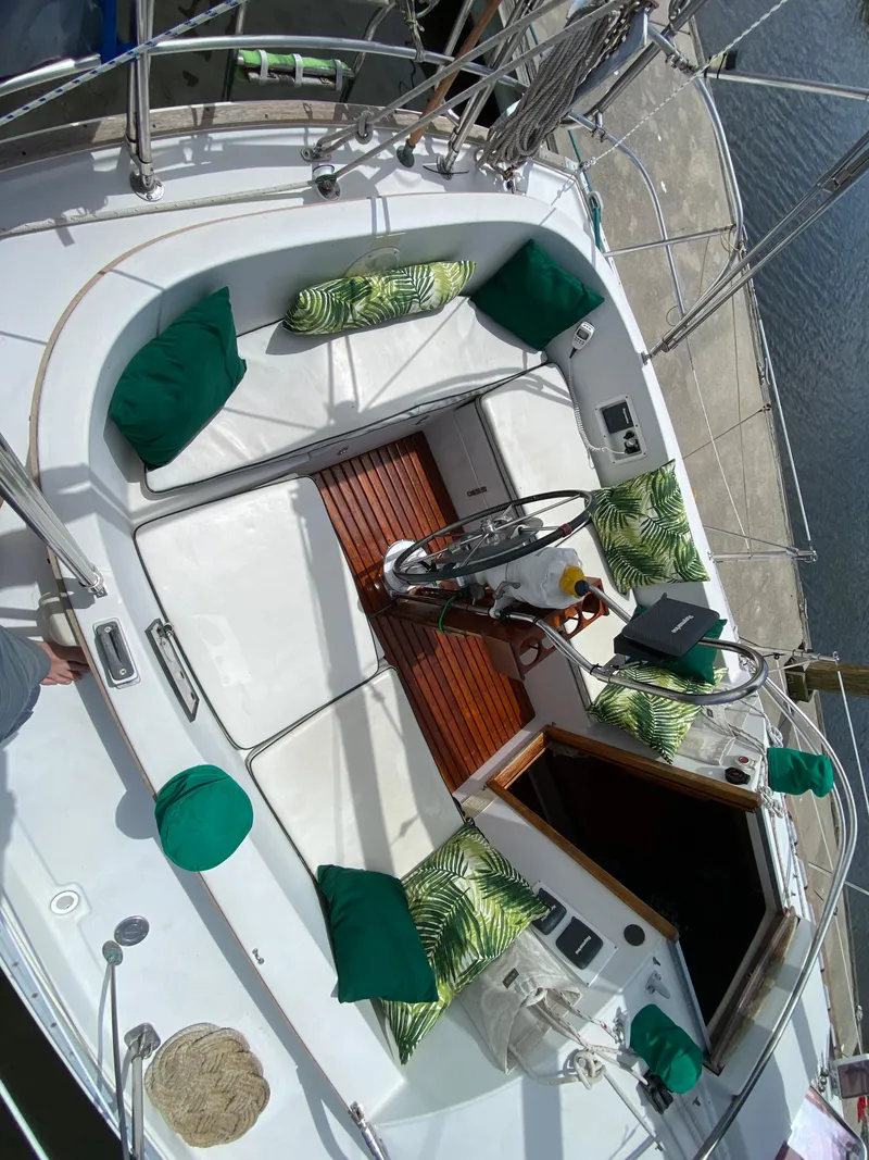 Slide: The Image of 1986 Nonsuch 30 Ultra sailboat cockpit with green cushions and wooden flooring. - 15