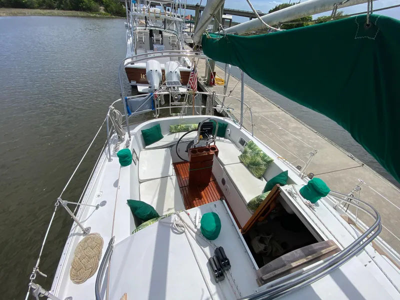 Slide: The Image of 1986 Nonsuch 30 Ultra sailboat docked, featuring green cushions and a spacious cockpit. - 16