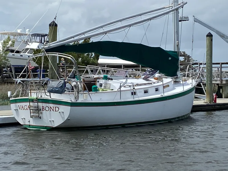 Slide: The Image of 1986 Nonsuch 30 Ultra sailboat docked at marina, green trim, overcast sky. - 2