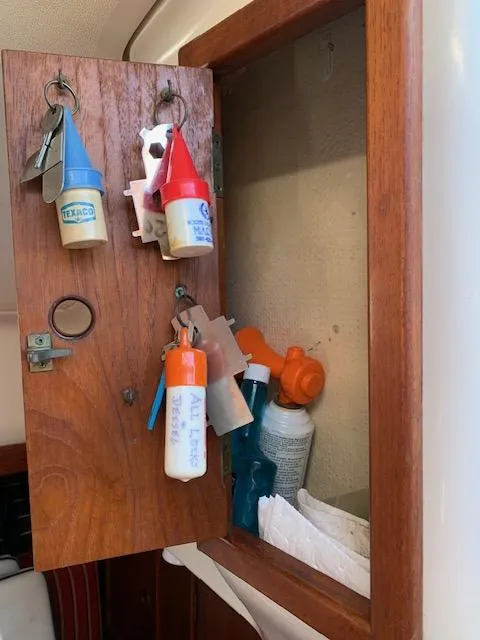 Slide: The Image of Wooden cabinet with nautical keychains and cleaning supplies on a 1986 Nonsuch 30 Ultra sailboat. - 28