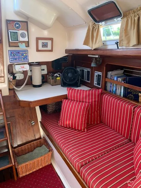Slide: The Image of Cozy 1986 Nonsuch 30 Ultra sailboat interior with red-striped seating and navigation equipment. - 32