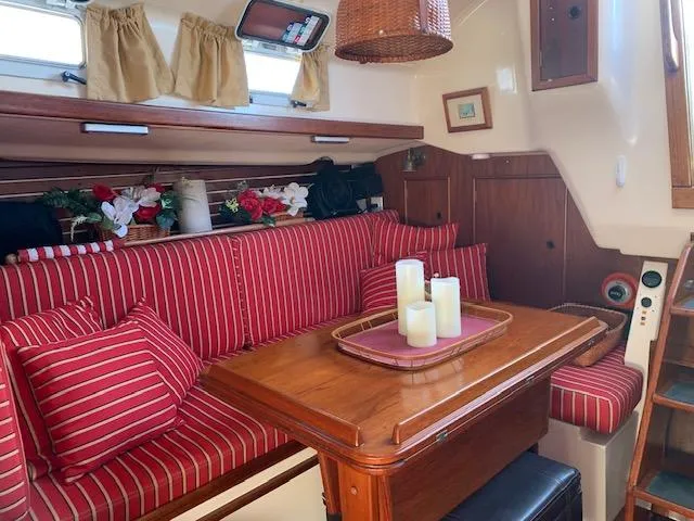 Slide: The Image of Cozy 1986 Nonsuch 30 Ultra sailboat interior with striped seating and wooden table. - 34