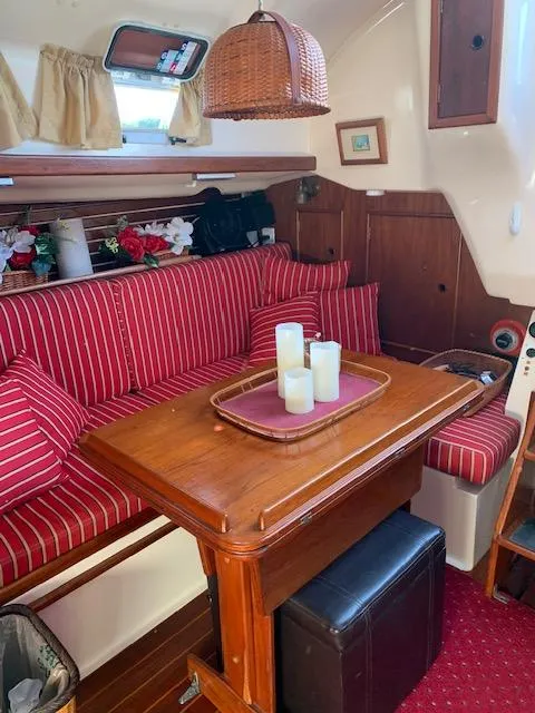 Slide: The Image of 1986 Nonsuch 30 Ultra sailboat interior with red-striped seating and wooden table. - 35