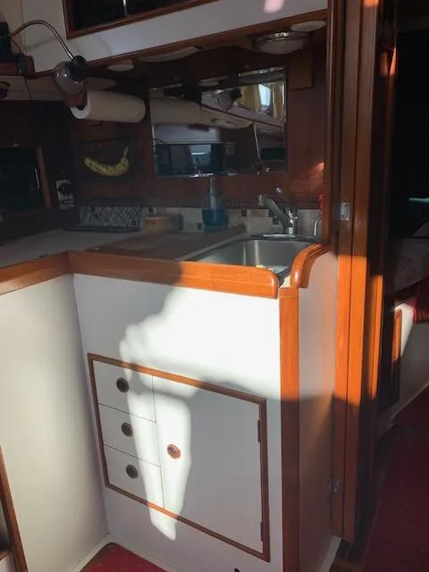 Slide: The Image of 1986 Nonsuch 30 Ultra yacht interior with wooden cabinetry and compact kitchen area. - 36