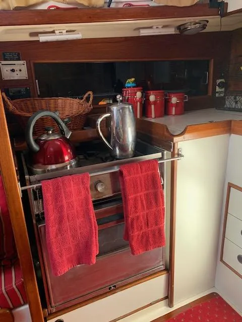 Slide: The Image of 1986 Nonsuch 30 Ultra yacht kitchen with stove, red kettle, and utensils. - 37