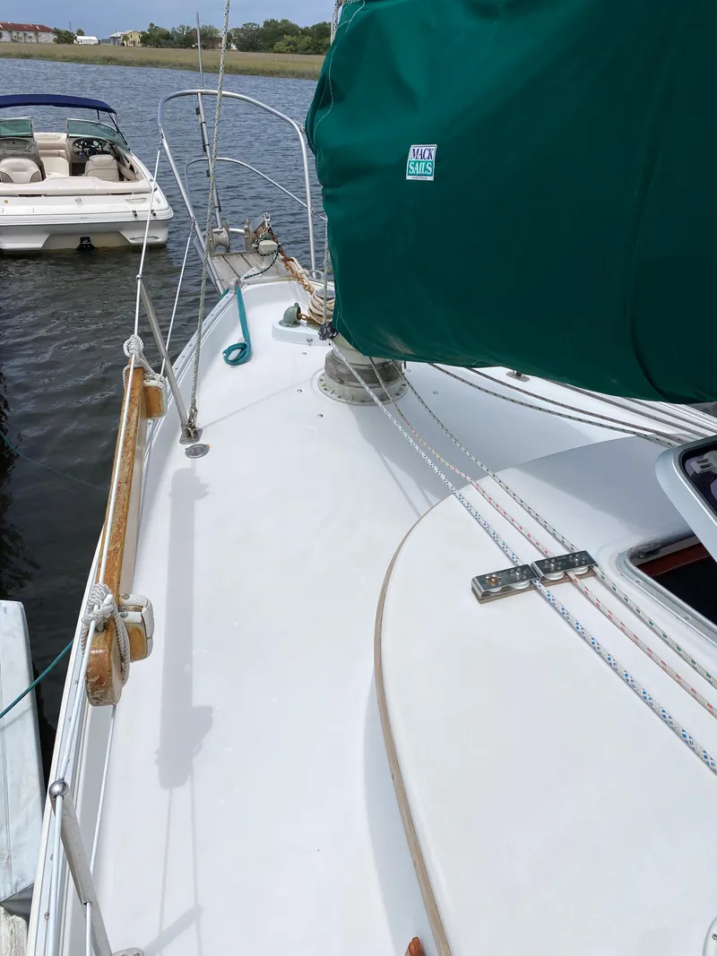 Slide: The Image of 1986 Nonsuch 30 Ultra sailboat deck with green sail cover, docked near another boat. - 8