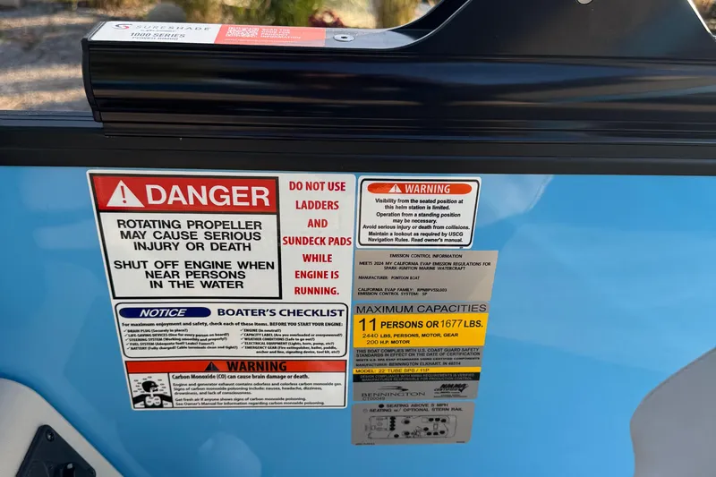 Slide: The Image of Warning labels on a 2025 Bennington 23 SSB boat, highlighting safety precautions and capacity limits. - 11