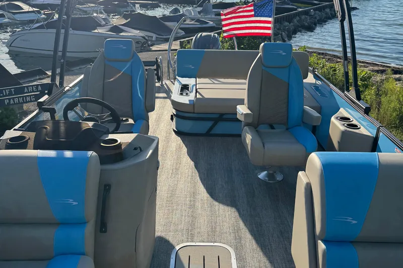 Slide: The Image of 2025 Bennington 23 SSB pontoon boat interior with blue and beige seating, docked by the water. - 20