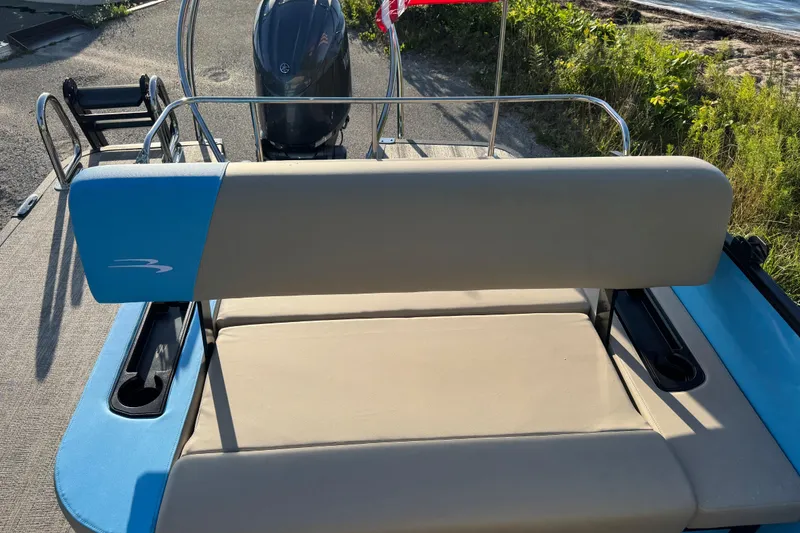 Slide: The Image of 2025 Bennington 23 SSB boat with beige and blue seating, near water. - 22