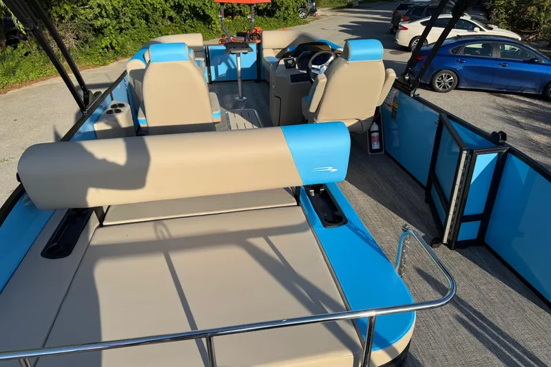Slide: The Image of 2025 Bennington 23 SSB pontoon boat with beige and blue seating, parked outdoors. - 9
