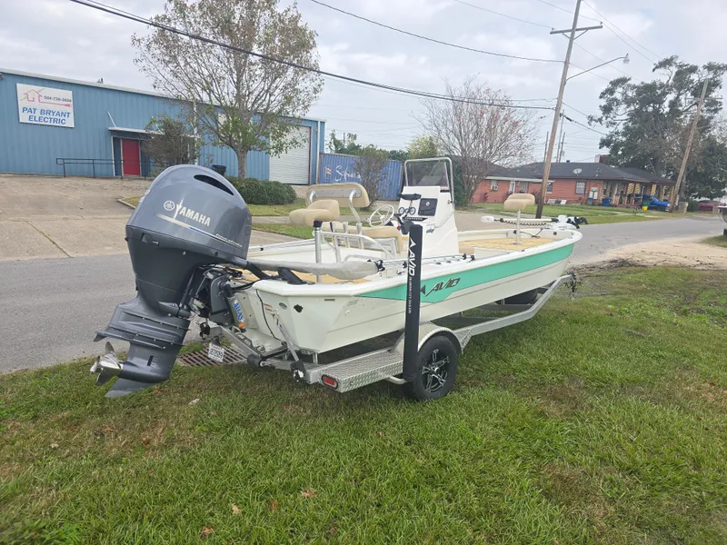 Slide: The Image of 2022 Avid 21 Mag boat on trailer, parked on grass near industrial buildings. - 12