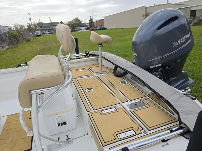 Slide: The Image of Avid 21 Mag 2022 boat with Yamaha engine, beige seating, and deck on grassy area. - 9