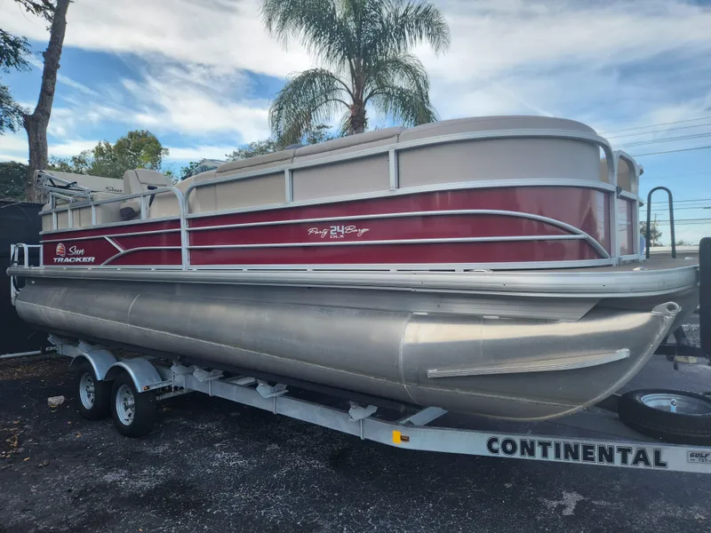 Slide: The Image of 2019 Sun Tracker 24 DLX Party Barge pontoon boat on trailer, parked outdoors. - 11