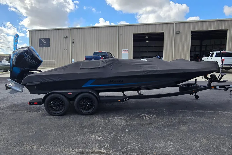 Slide: The Image of Covered iKon LXL21 boat on trailer, parked outside a warehouse, 2025 model. - 26
