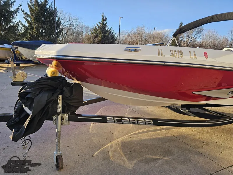 Slide: The Image of 2018 Scarab 165 ID boat on trailer, red and white, parked outdoors. - 11