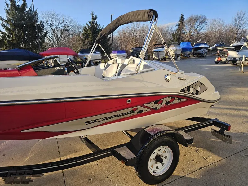 Slide: The Image of 2018 Scarab 165 ID boat on trailer, red and white design, parked outdoors. - 17