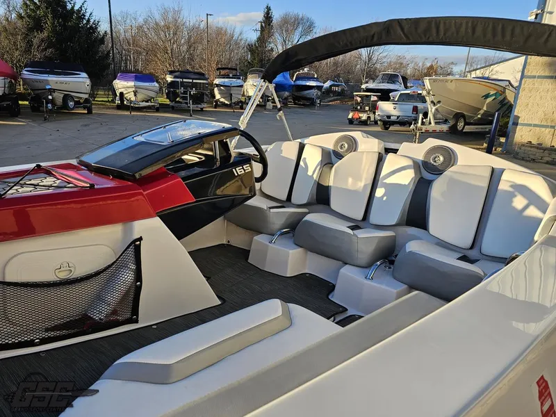 Slide: The Image of 2018 Scarab 165 ID boat interior with seating and steering wheel, parked among other boats. - 33