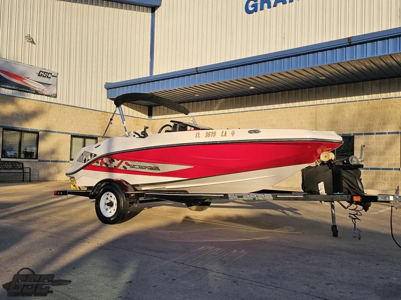 Slide: The Image of 2018 Scarab 165 ID boat on trailer, red and white design, parked outside a building. - 6