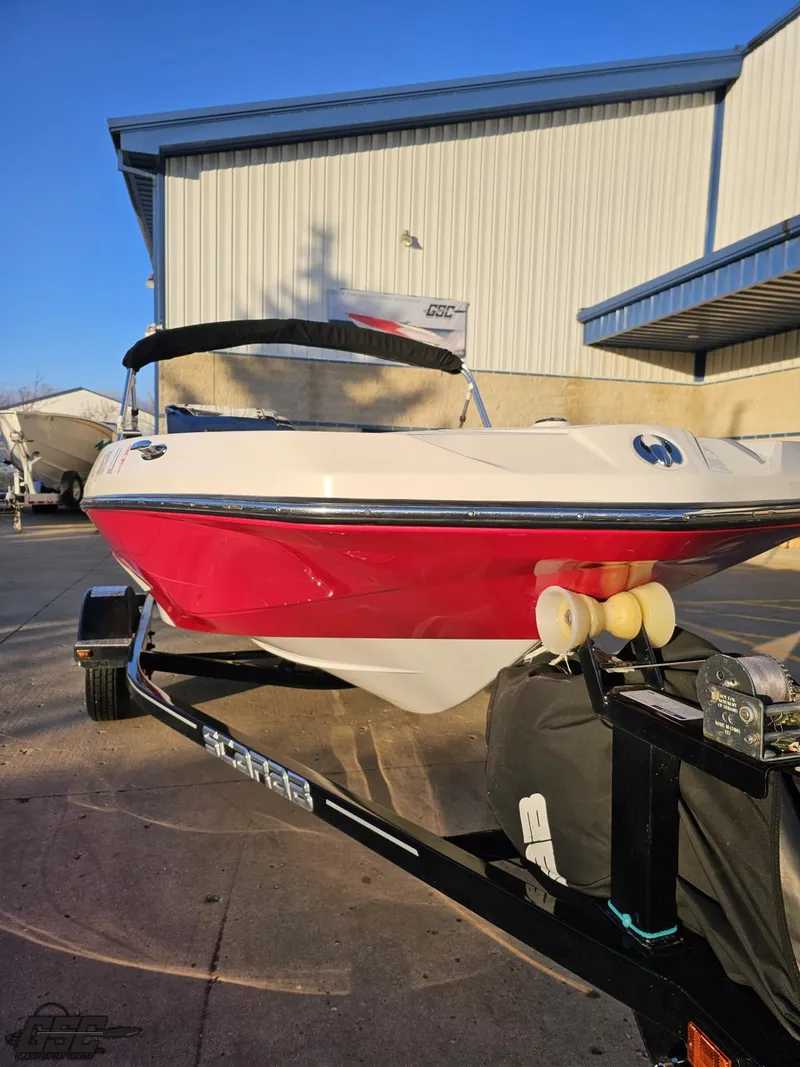Slide: The Image of 2018 Scarab 165 ID boat with red hull on trailer, parked outside a warehouse. - 8