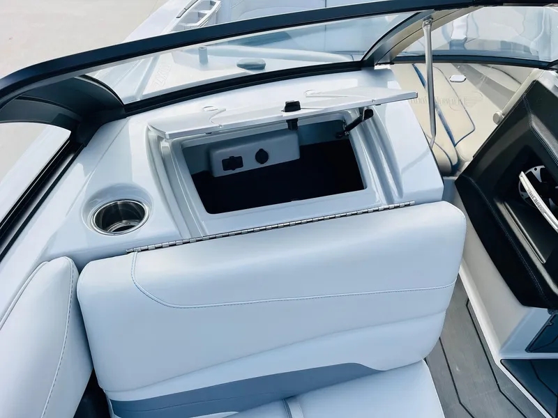 Slide: The Image of 2020 Malibu Wakesetter 24 MXZ interior with open storage compartment and cup holder. - 18