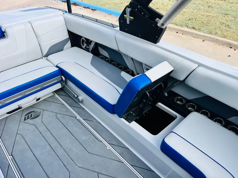 Slide: The Image of 2020 Malibu Wakesetter 24 MXZ interior with blue and white seating, open storage compartment. - 24