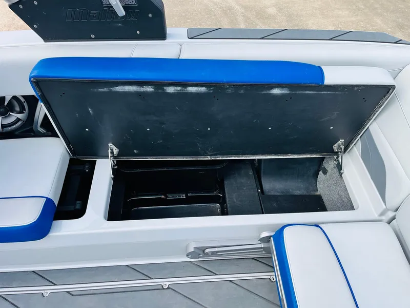 Slide: The Image of 2020 Malibu Wakesetter 24 MXZ boat storage compartment with blue and white seating. - 34