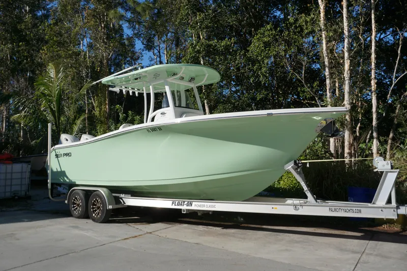 Slide: The Image of 2021 Sea Pro 259 Center Console boat on trailer, surrounded by trees. - 0