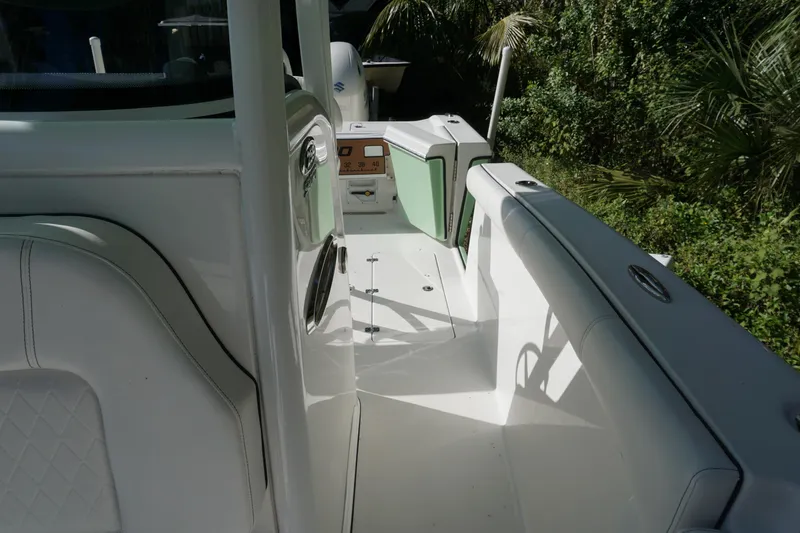 Slide: The Image of 2021 Sea Pro 259 Center Console boat interior with white seating and lush greenery background. - 14