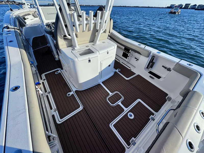 Slide: The Image of 2021 Tidewater 320 CC Adventure boat with spacious deck and rod holders on the water. - 2