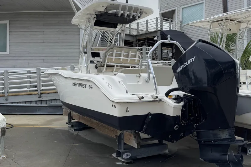 Slide: The Image of 2021 Key West 239 FS boat with Mercury engine, docked near a modern building. - 2