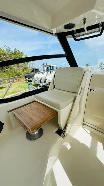 Slide: The Image of 2023 Boston Whaler 325 interior with seating and wooden table, showcasing luxury design. - 11