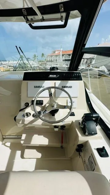 Slide: The Image of 2023 Boston Whaler 325 boat cockpit with steering wheel and Simrad navigation system. - 14