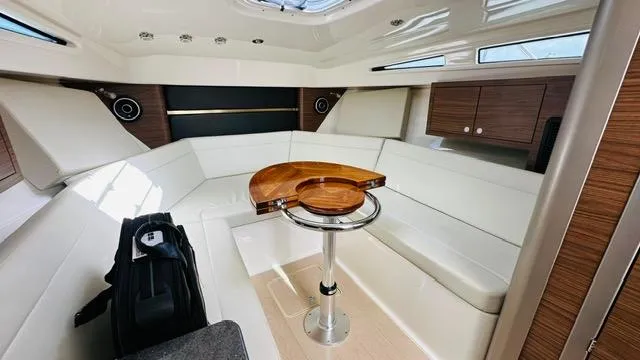 Slide: The Image of 2023 Boston Whaler 325 cabin interior with white seating, wooden accents, and a central table. - 17