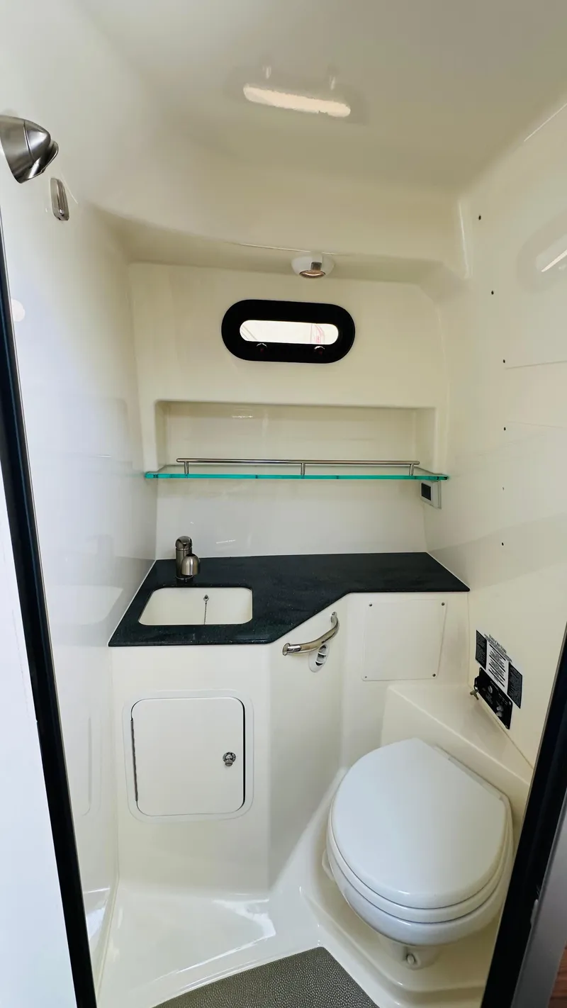 Slide: The Image of 2023 Boston Whaler 325 boat interior bathroom with sink, toilet, and shelf. - 19