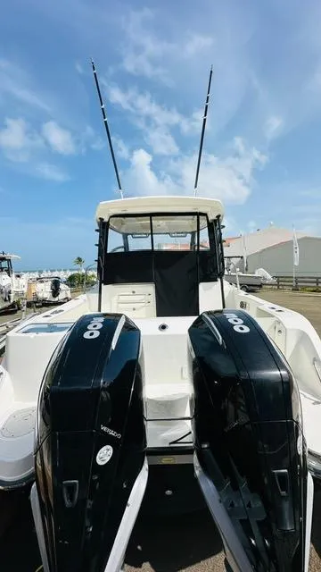 Slide: The Image of 2023 Boston Whaler 325 boat with dual engines, docked under a clear blue sky. - 3