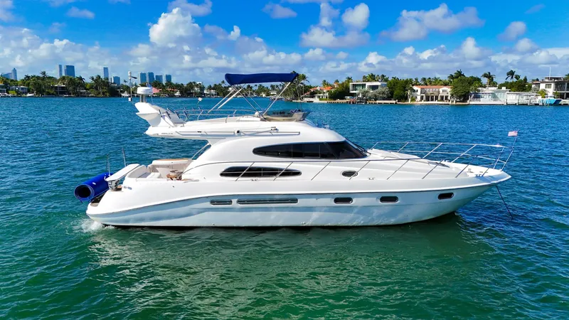 Slide: The Image of 2004 Sealine 47 yacht cruising on a sunny day with city skyline in background. - 0