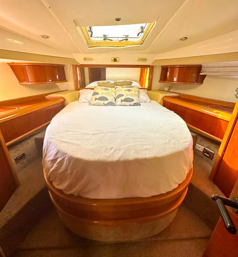 Slide: The Image of Luxurious cabin interior of a 2004 Sealine 47 yacht with a cozy bed and wooden accents. - 27