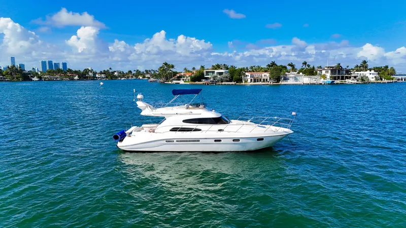 Slide: The Image of 2004 Sealine 47 yacht on blue water, clear sky, coastal background. - 5