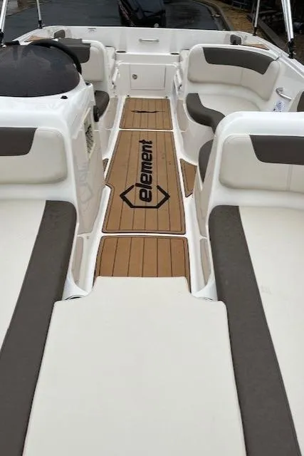 Slide: The Image of 2023 Bayliner Element E18 boat interior with cushioned seating and wood-style flooring. - 2