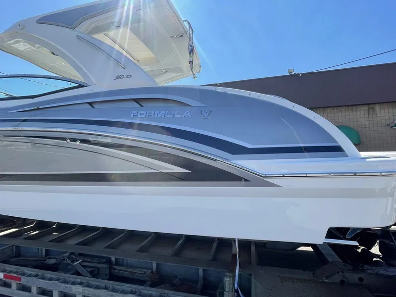 Slide: The Image of 2026 Formula 310 Sun Sport boat on trailer under clear blue sky. - 12