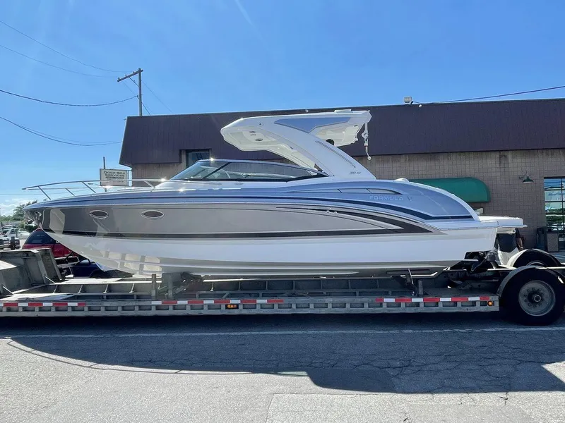 Slide: The Image of 2026 Formula 310 Sun Sport boat on trailer, parked outside a building under clear blue sky. - 13