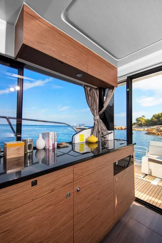 Slide: The Image of Family enjoying a meal on a 2025 Jeanneau NC 1095 Weekender boat interior. - 11