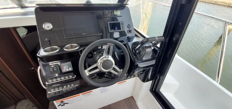 Slide: The Image of Interior view of 2025 Jeanneau NC 1095 Weekender boat cockpit with marina background. - 13